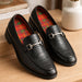 Black leather loafers with plaid insoles and a silver buckle on a wooden surface.