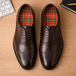 Brown dress shoes with plaid lining on a wooden surface