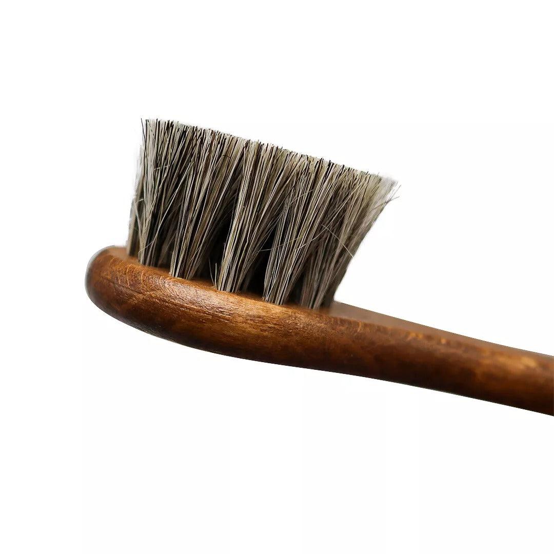 Grey horsehair dauber brush reaching intricate stitching on leather shoes