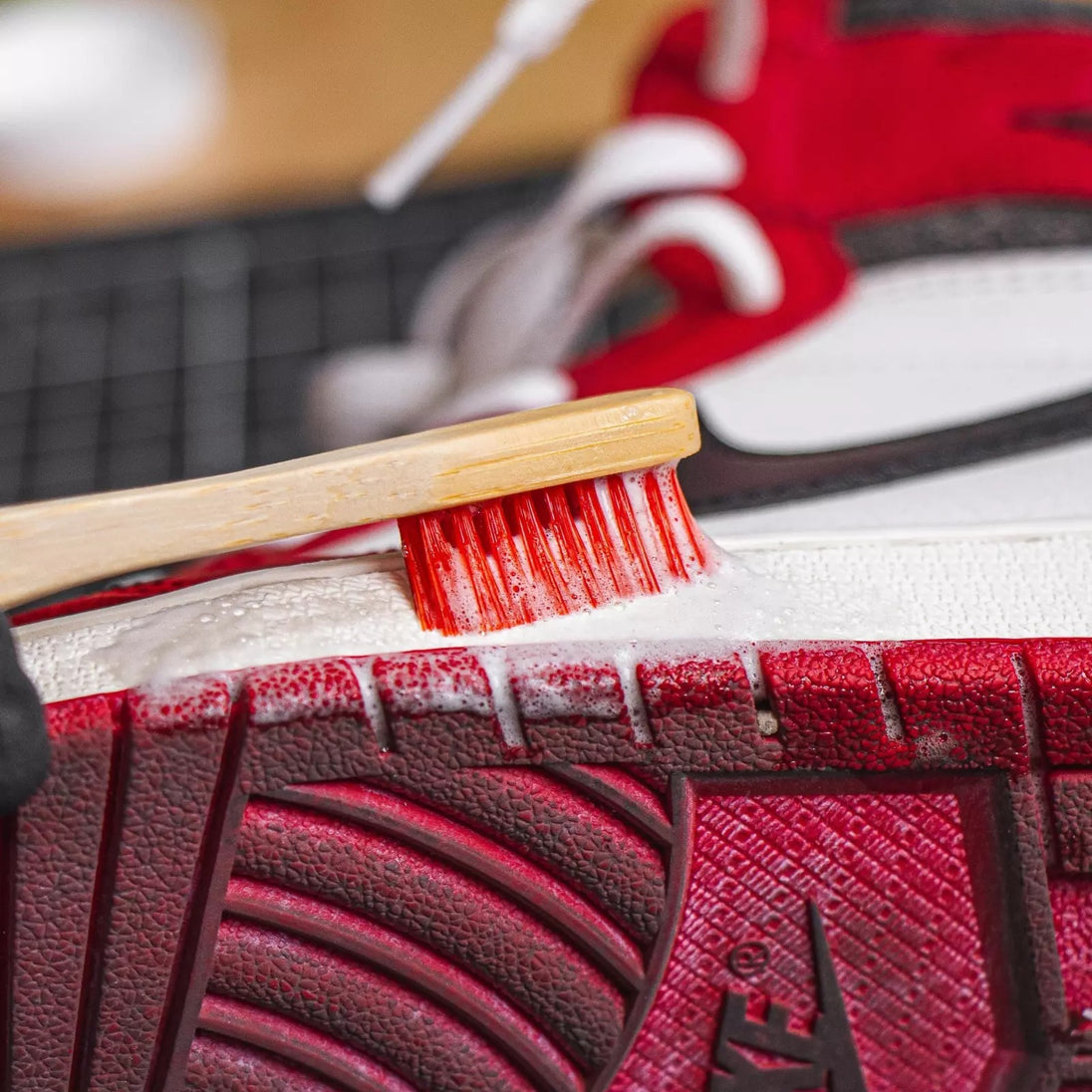 Using the stiff-bristled Angelus bamboo brush to scrub ground-in dirt from a sneaker sole demonstrating its effective cleaning power