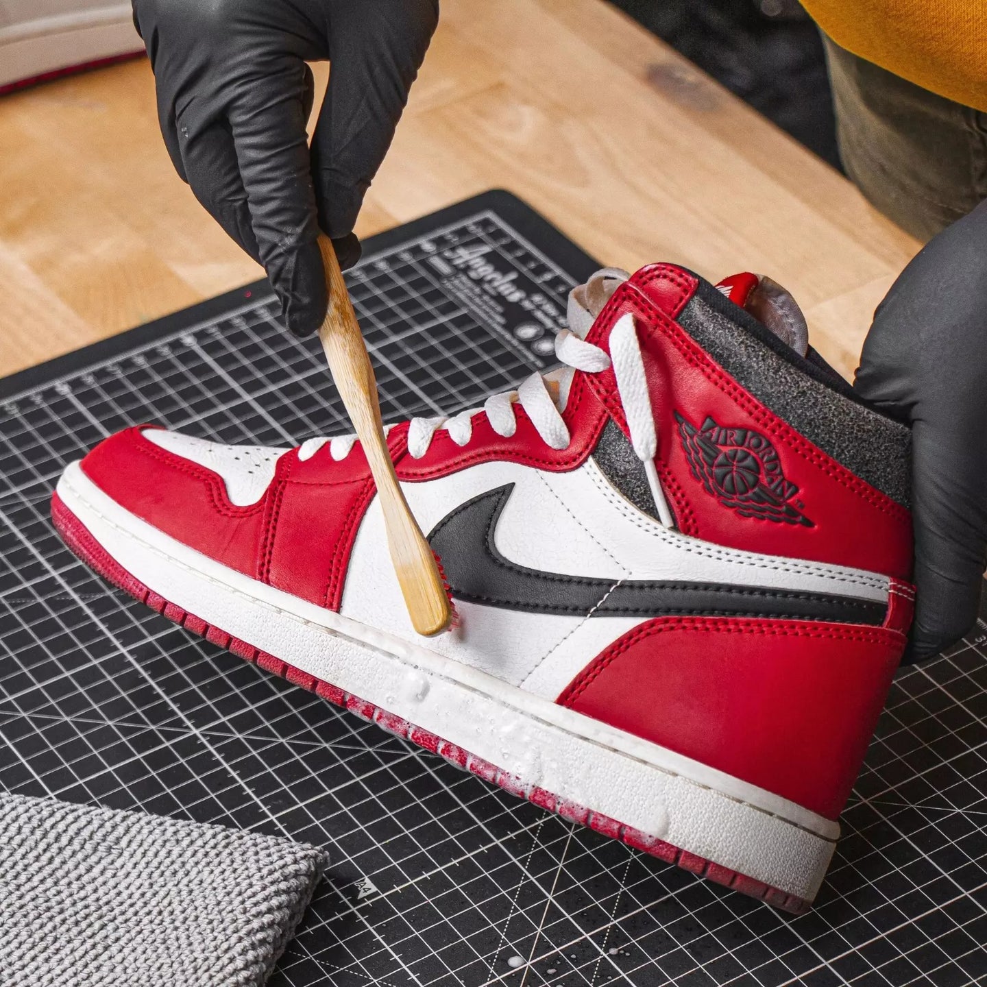 The soft-bristled Angelus bamboo detail brush gently cleaning a suede sneaker panel perfect for delicate materials without damage